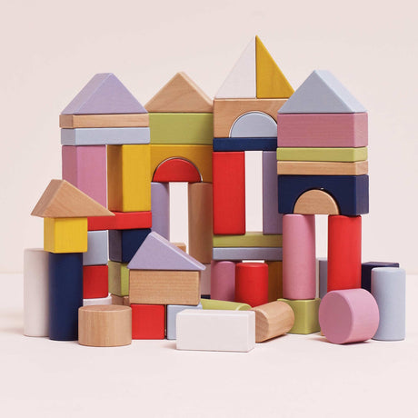 Colorful pastel wooden building blocks assembled into miniature castle and tower structures.