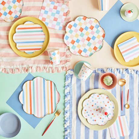Festive party table setting with colorful plates, napkins, cups, tablecloths, and cutlery.