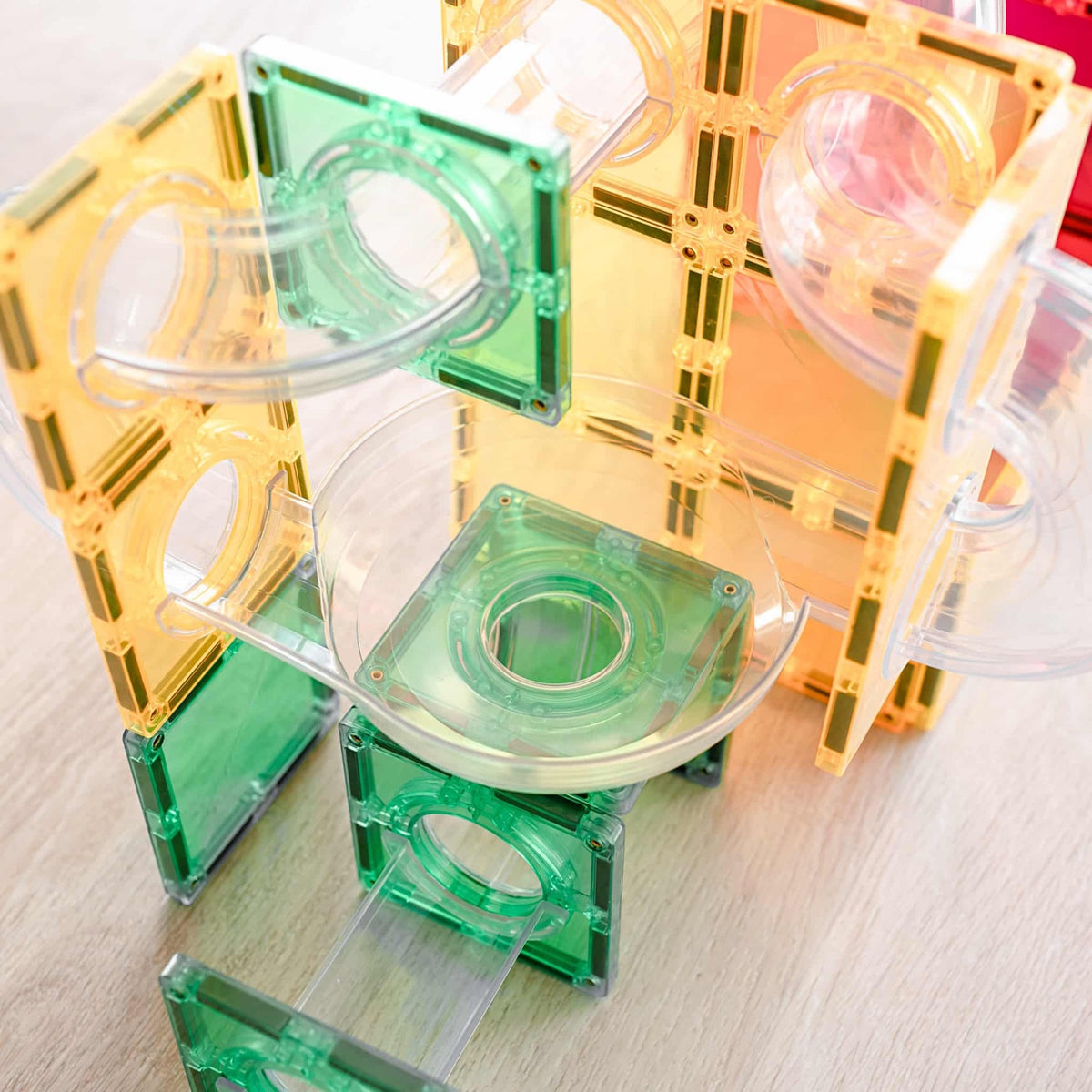 Close-up of a colorful magnetic tile ball run structure with clear tubes and a funnel piece.