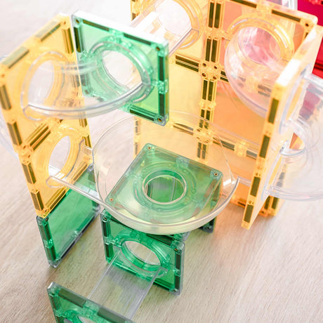 Close-up of a colorful magnetic tile ball run structure with clear tubes and a funnel piece.