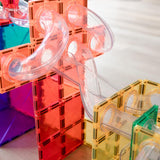 Close-up of a colorful Connetix magnetic tile ball run structure with clear curved tubes attached to tiles.