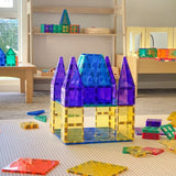 Colorful toy castle built with magnetic tiles on a play mat in a sunlit playroom.