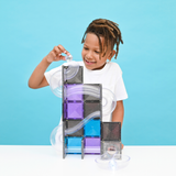 Young boy placing a clear ball into a magnetic tile ball run structure.