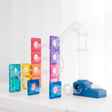 Colorful magnetic tile ball run structure with clear tubes and a blue launcher on a white surface.