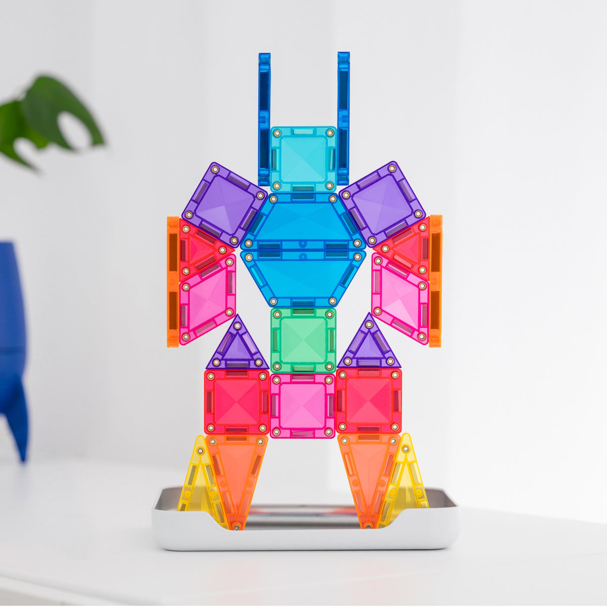 Colorful magnetic tile figure built in a robot shape with blue, purple, pink, and yellow geometric pieces.