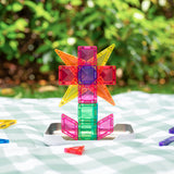 Colorful magnetic tiles built into a flower structure resting on a green checkered picnic blanket.