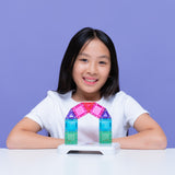 Smiling young girl sitting behind a colorful magnetic tile arch against a purple backdrop.