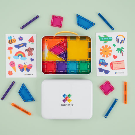 Colorful magnetic building tile set in a travel case with sticker sheets on a light green background.