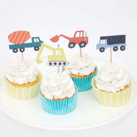 Cupcakes with swirled white frosting, construction vehicle toppers, and shiny striped baking cups on a white plate.