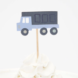 Blue dump truck cupcake topper on a wooden pick in swirled white frosting.