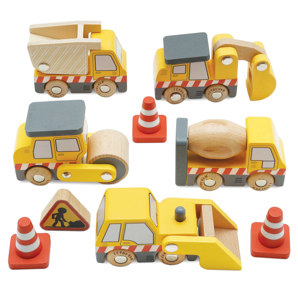 Wooden toy construction vehicles, including a dump truck, excavator, road roller, and cement mixer, are surrounded by traffic cones and a caution sign.
