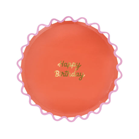 Meri Meri coral Happy Birthday paper plate with a pink wiggle scalloped edge and gold foil script.
