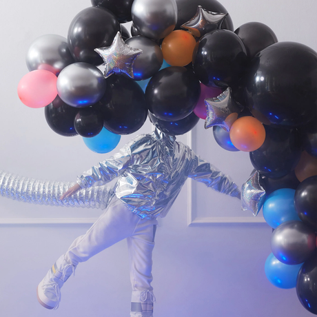 Cosmic balloon garland displayed with a person dressed in a metallic silver space suit outfit.