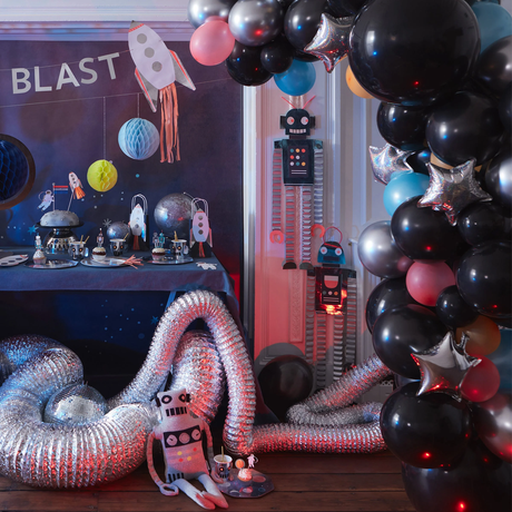 Cosmic balloon arch framed beside a space-themed party setup with rockets, planets, and robot decorations.