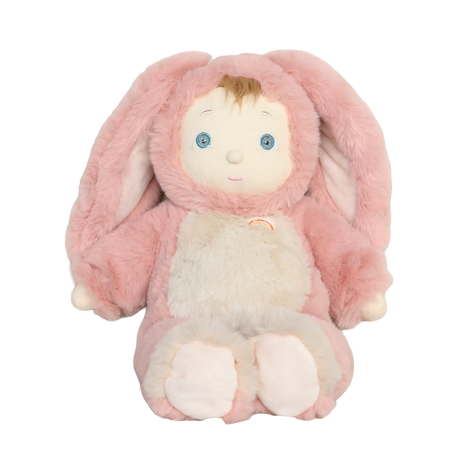 Plush baby doll wearing a fuzzy pink bunny suit with long floppy ears and a small rainbow patch.