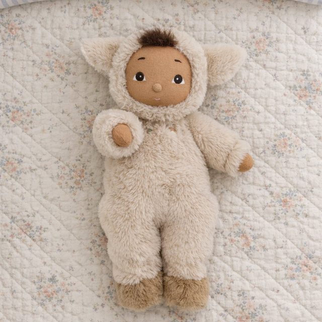 Olli Ella Cozy Dinkum Lamby plush doll on a floral quilted blanket.