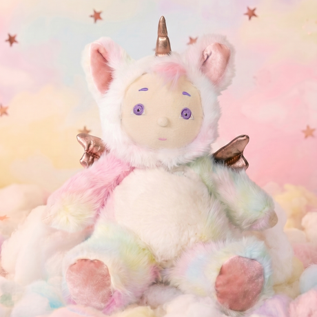 Plush baby doll in a pastel rainbow tie-dye unicorn onesie sitting on fluffy clouds with stars.