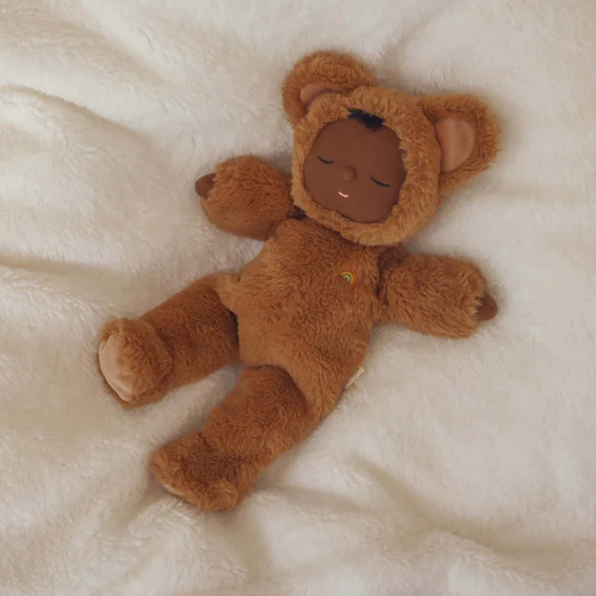 Olli Ella Cozy Dinkum Teddy Mini Caramel doll sleeping on a soft white blanket.