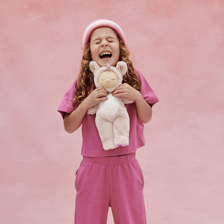 Olli Ella Cozy Dinkum Unicorn Sugarpie plush doll hugged by a happy child.