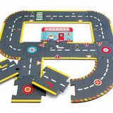 Children's puzzle road set with interconnected pieces showing roads, traffic signs, and a garage illustration. Vibrant and playful design.