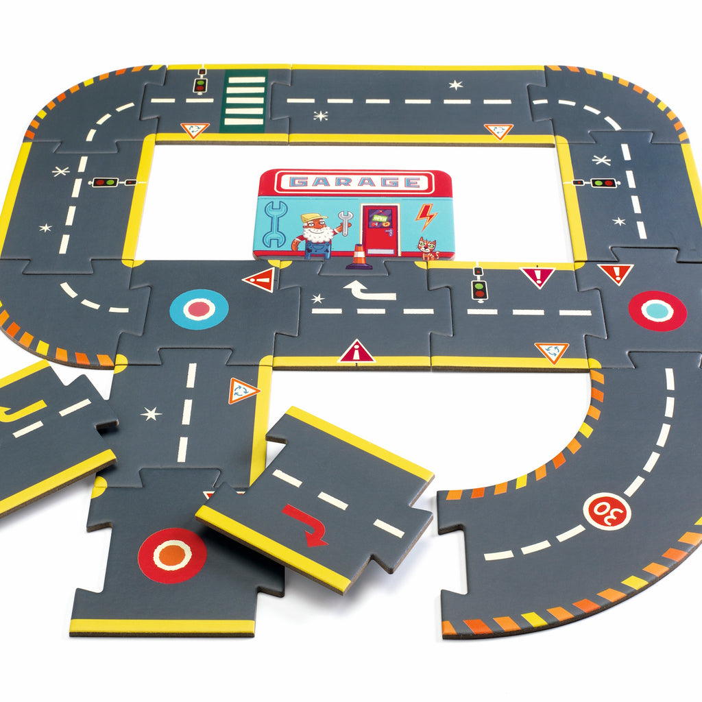 Children's puzzle road set with interconnected pieces showing roads, traffic signs, and a garage illustration. Vibrant and playful design.