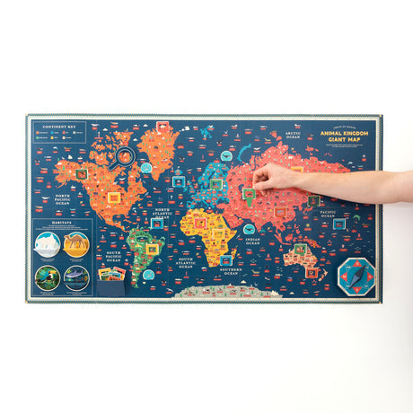 A hand placing a pop-up piece onto a large, colorful world map labeled "Animal Kingdom Giant Map."
