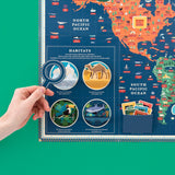 Hand holding a paper magnifying glass over an illustrated animal kingdom map with habitat pop-ups.