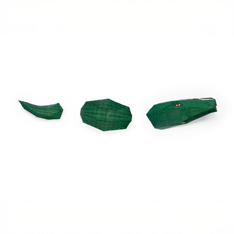 Three green papercraft crocodile sections, head, body, and tail, aligned on a white background.