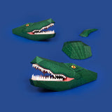 3D papercraft green crocodile model assembled in sections set against a solid blue background.