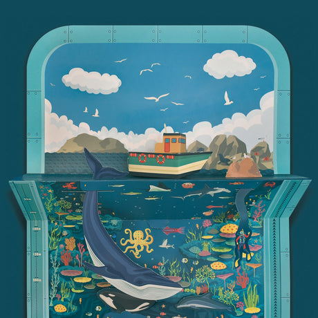 3D papercraft seascape diorama featuring a boat above water and a large blue whale swimming below.