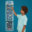 Young boy pointing at a vertical ocean layer activity craft hanging against a blue background.
