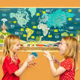 Two young girls excitedly playing with dinosaur cutouts in front of a large, colorful dinosaur world map.