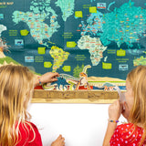 Two young girls interacting with a dinosaur timeline activity set in front of a illustrated world map.