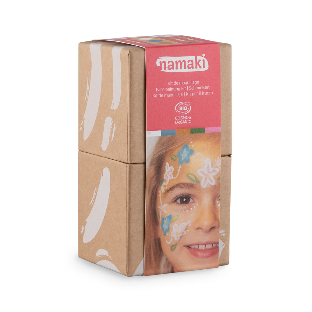 Close-up of Namaki Flower Fairy Face Painting Kit in sustainable cardboard packaging with a smiling child displaying floral-themed face paint.