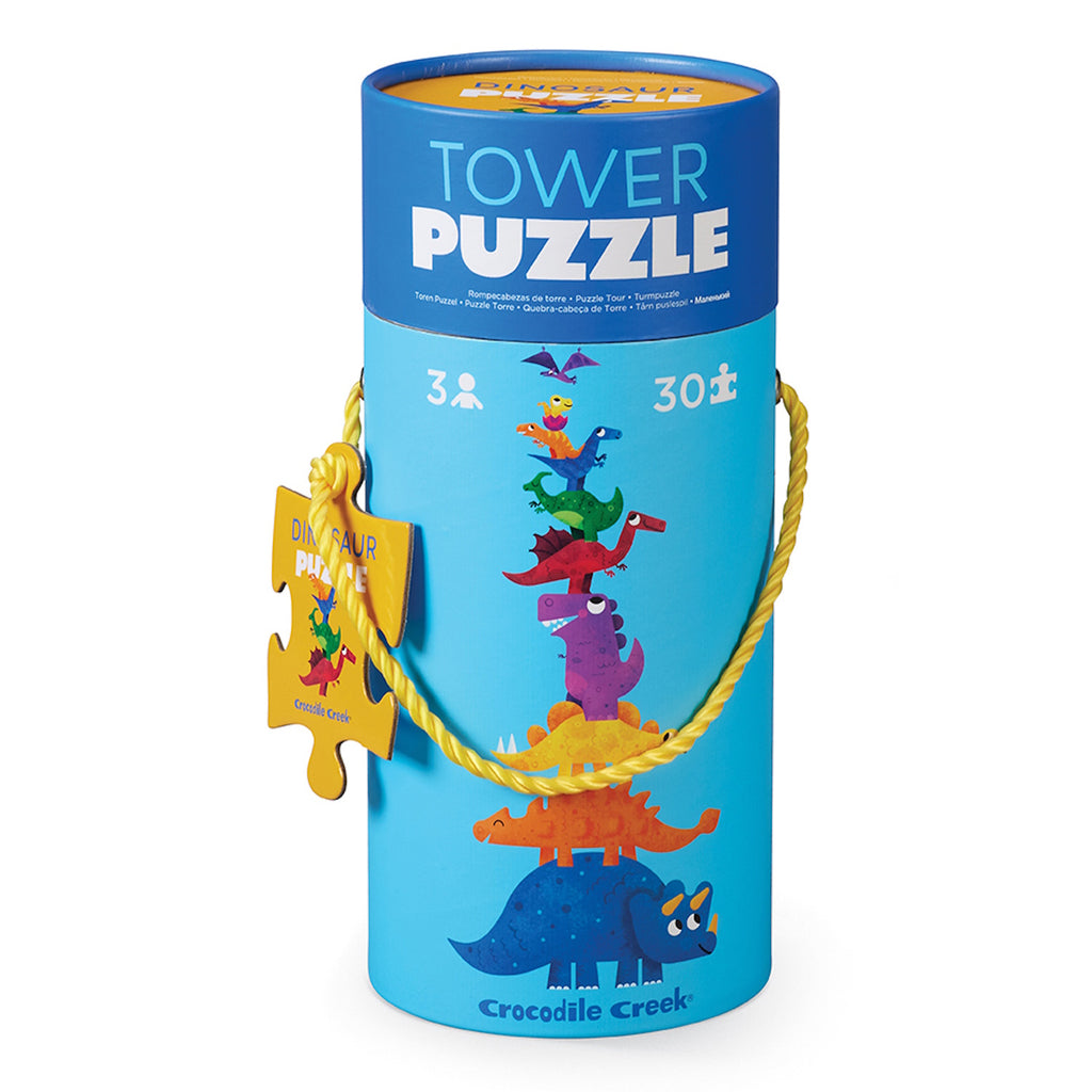 Bright cylindrical container with a "Tower Puzzle" label, featuring colorful cartoon dinosaurs stacked in a playful tower. Includes a yellow rope handle and puzzle piece tag.