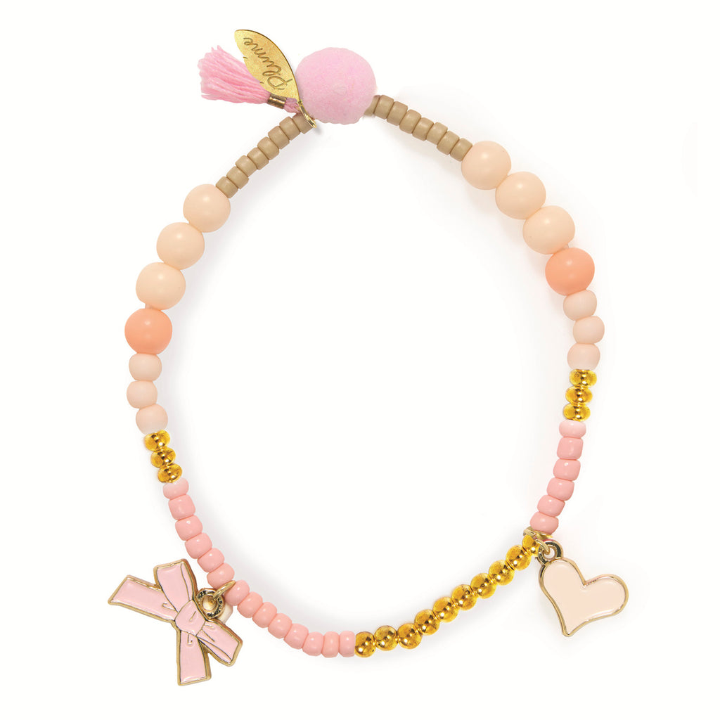 Pastel beaded bracelet with gold accents, featuring pink bow and heart charms. A pink pom-pom and tassel add a playful touch.