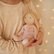 Child holding a blonde plush fairy doll with wings and a rainbow dress.