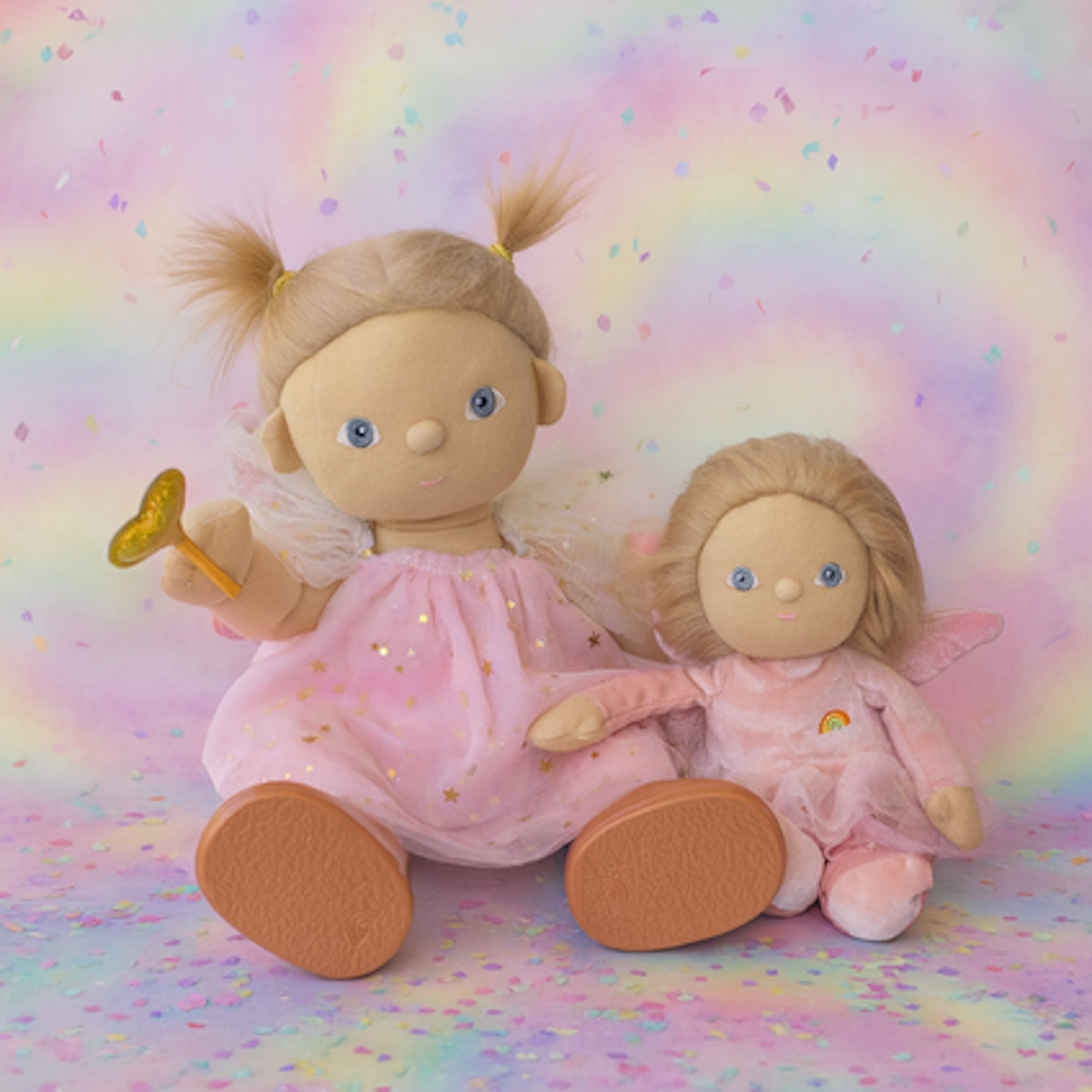 Two Olli Ella Dinkum dolls dressed as pink fairies with wings, sitting on a colorful rainbow background.
