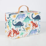 Closed dinosaur advent calendar suitcase with leather handle, metal clasp, and colorful dinosaur pattern.