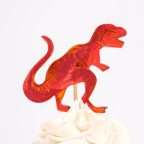Red T-Rex dinosaur cupcake topper on a wooden pick in swirled white frosting.