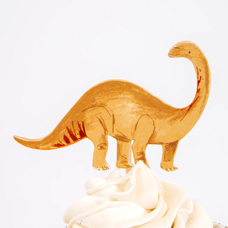 Gold long-necked dinosaur cupcake topper on a wooden pick in swirled white frosting.