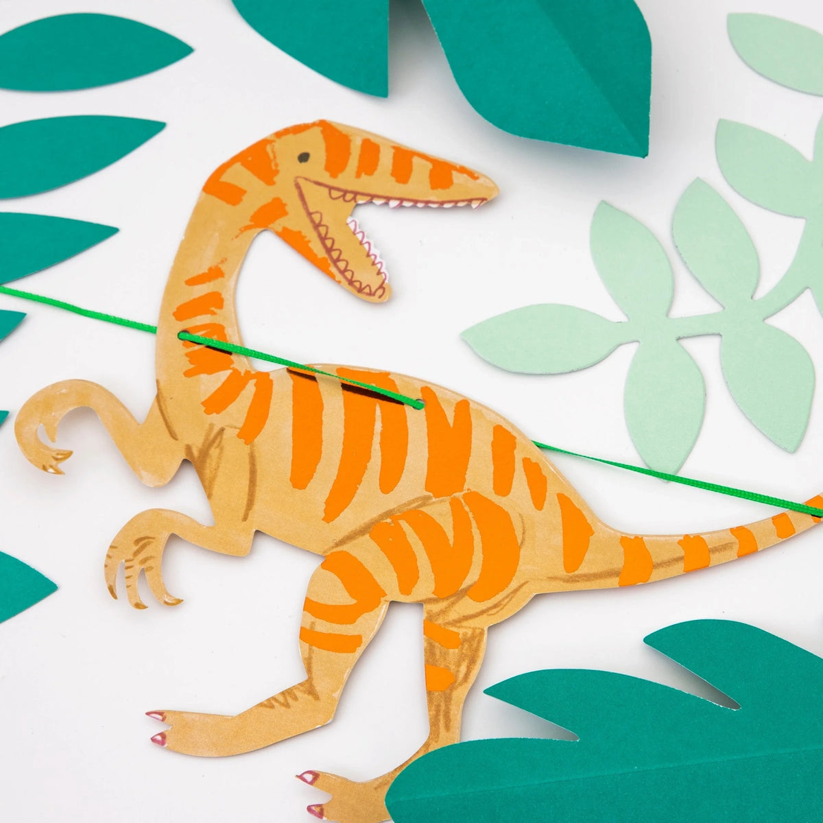 Detailed view of an orange striped dinosaur paper cutout on a garland strand.