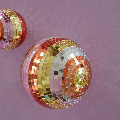 A striped gold, orange, and silver disco ball on a purple background.