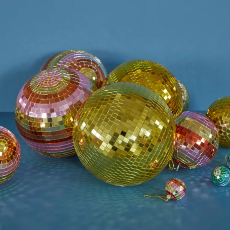 A collection of shiny gold and pink striped disco balls of various sizes against a solid blue background.
