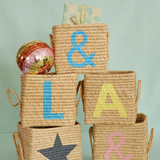 Stacked woven baskets painted with letters, symbols, and a star, topped with a colorful disco ball.