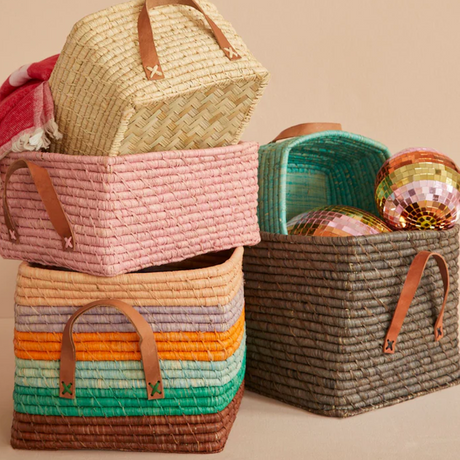 Colorful stacked woven storage baskets with leather handles, holding a couple of shiny disco balls.