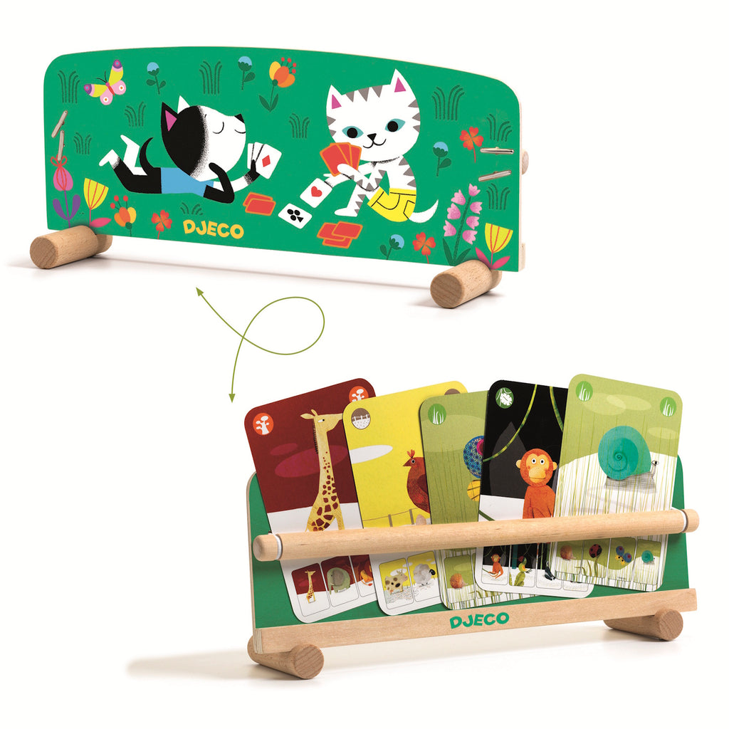 A green cardholder with wooden legs holds illustrated cards featuring animals like giraffes and snails. Playful cats and flowers are printed on the board.