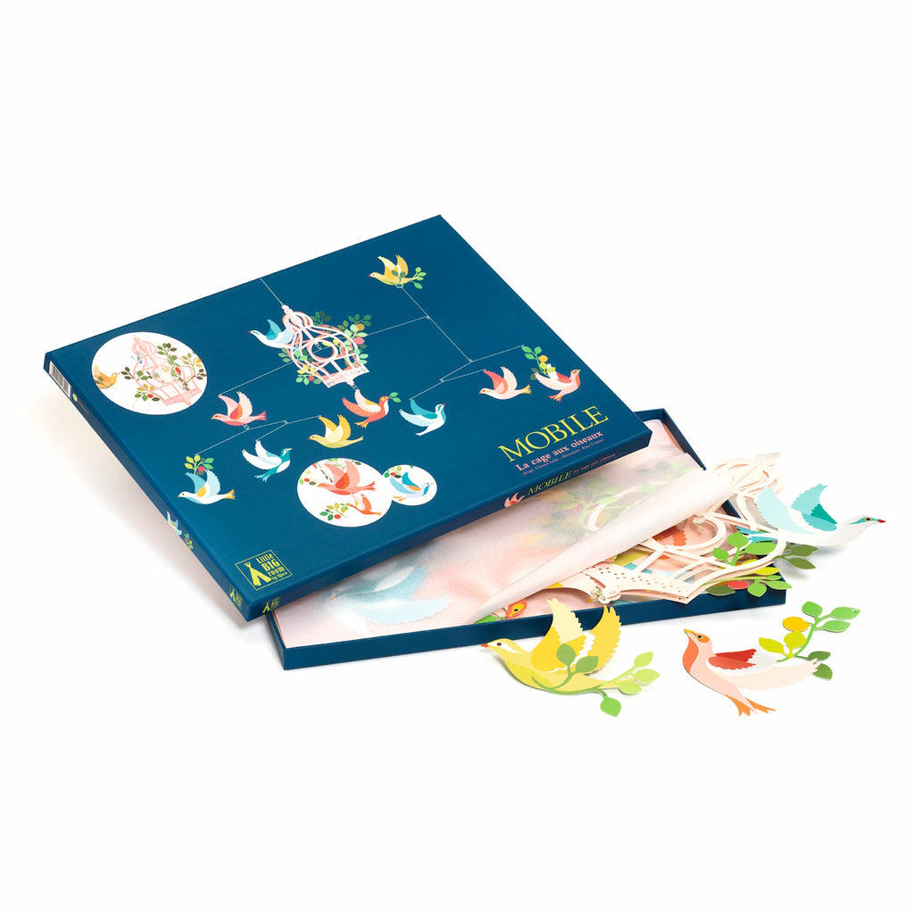 Box of decorative bird mobile pieces. The dark blue box, slightly open, reveals colorful paper birds and foliage, with vibrant, playful tones.