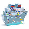 Illustrated box shaped like a ship with cartoon sailors waving, and passengers visible through portholes. Fun, playful design for ages 5+.