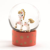 Djeco mini snow globe with a white horse, gold stars, and pink floral detail on an orange base with gold stars.